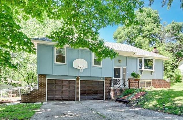 7608 N Serene Ave, Kansas City, MO 64152 - raised ranch featuring brick siding, an attached garage, driveway, and a chimney