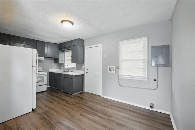 5609 E 101st St, Kansas City, MO 64137 - kitchen with white appliances, electric panel, light countertops, a sink, and dark wood-style floors