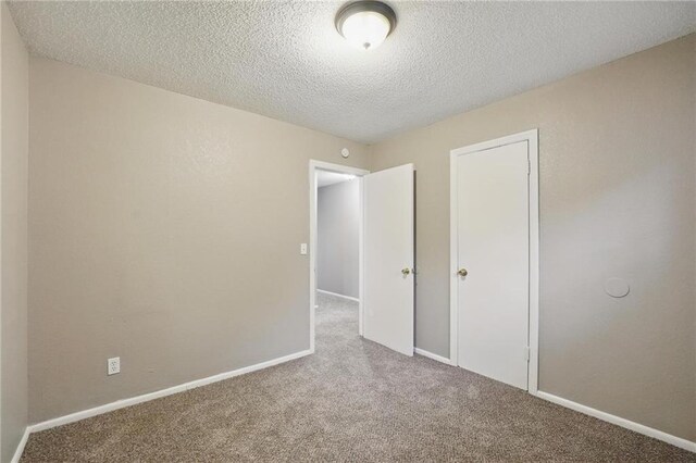 5609 E 101st St, Kansas City, MO 64137 - unfurnished bedroom with carpet flooring, a textured ceiling, baseboards, and a closet