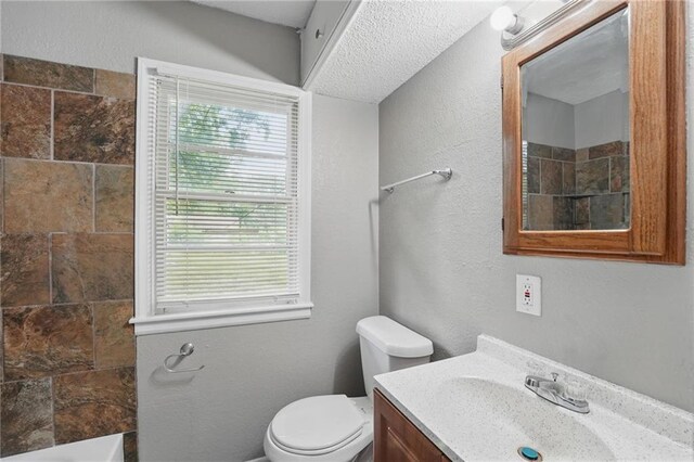 5609 E 101st St, Kansas City, MO 64137 - bathroom featuring a tile shower, toilet, vanity, plenty of natural light, and a textured wall