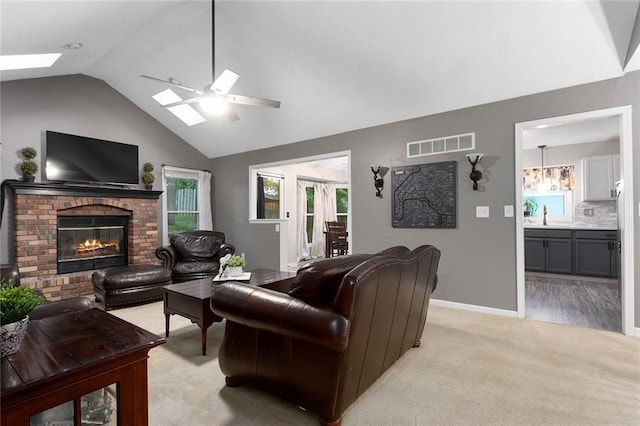 1512 Auburn Dr, Lees Summit, MO 64086 - living room with a skylight, a ceiling fan, a brick fireplace, baseboards, and light carpet