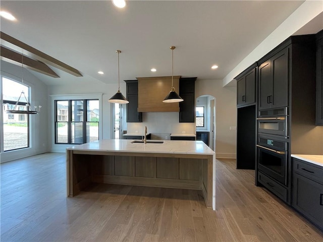 17000 Rosehill St, Overland Park, KS 66221 - kitchen with arched walkways, light wood-type flooring, lofted ceiling, a kitchen island with sink, and recessed lighting