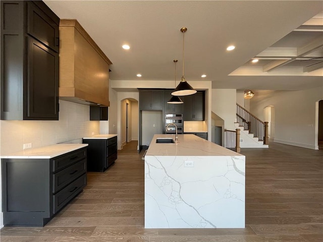 17000 Rosehill St, Overland Park, KS 66221 - kitchen with arched walkways, light stone countertops, wood finished floors, a center island with sink, and recessed lighting