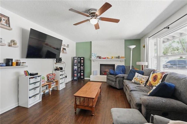 10621 E 32nd St, Independence, MO 64052 - living area with a ceiling fan, dark wood-style flooring, a textured ceiling, a brick fireplace, and baseboards