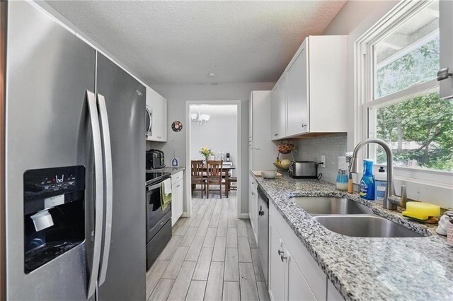 10621 E 32nd St, Independence, MO 64052 - kitchen with stainless steel appliances, a sink, white cabinetry, light wood-style floors, and a textured ceiling
