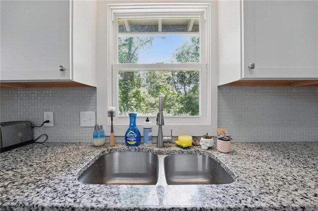 10621 E 32nd St, Independence, MO 64052 - kitchen view of a sink, white cabinetry, light stone counters, and backsplash