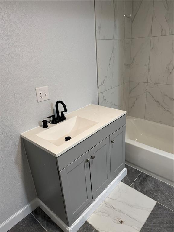116 N Home St, Independence, MO 64053 - bathroom featuring vanity, a textured wall, tub / shower combination, and baseboards