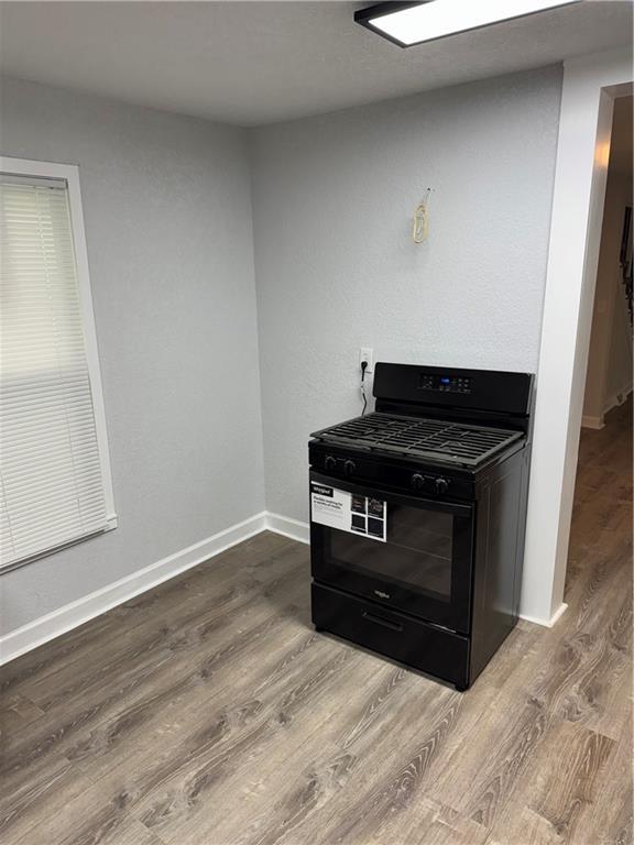 116 N Home St, Independence, MO 64053 - kitchen with black gas stove, wood finished floors, and baseboards
