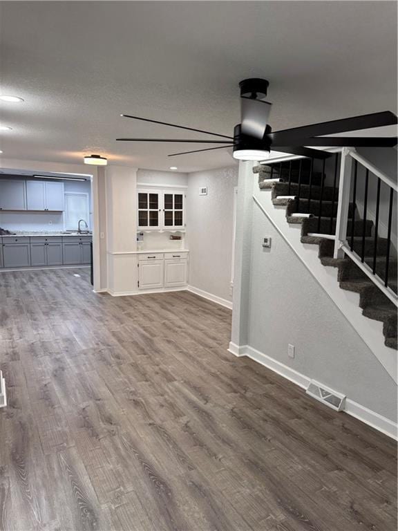 116 N Home St, Independence, MO 64053 - unfurnished living room with baseboards, stairs, dark wood-style floors, and a sink