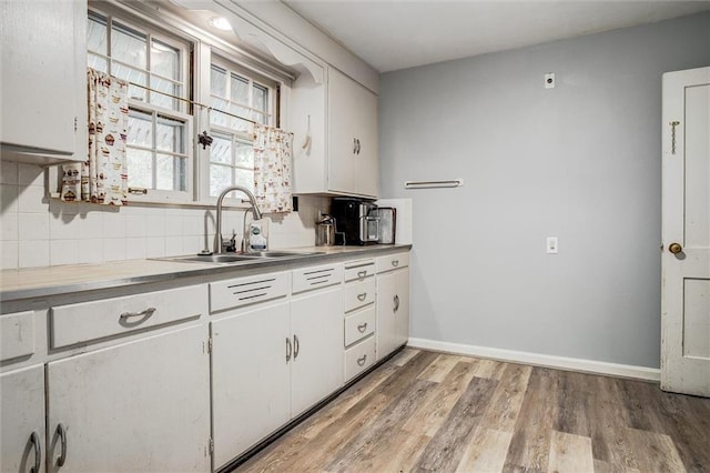 2738 S Crysler Ave, Independence, MO 64052 - kitchen featuring a sink, white cabinetry, decorative backsplash, light wood-type flooring, and baseboards