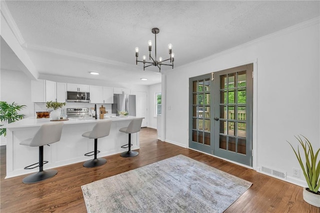 706 W Cedar St, Olathe, KS 66061 - kitchen with stainless steel appliances, ornamental molding, a textured ceiling, a kitchen bar, and french doors