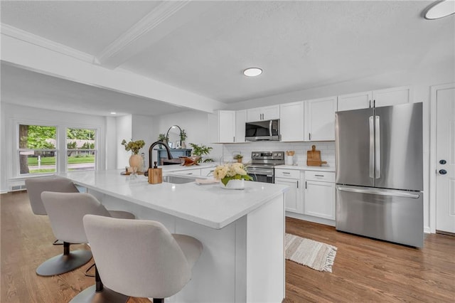 706 W Cedar St, Olathe, KS 66061 - kitchen with appliances with stainless steel finishes, a sink, white cabinetry, light countertops, and a kitchen breakfast bar