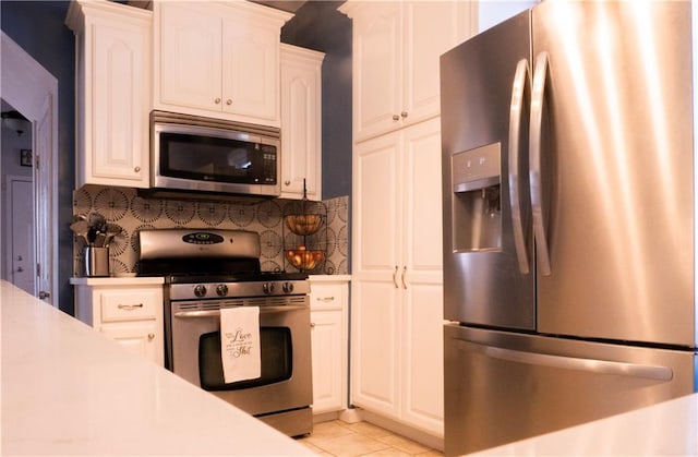 3812 Anderson Ave, Kansas City, MO 64132 - kitchen featuring stainless steel appliances, backsplash, white cabinets, light countertops, and light tile patterned floors