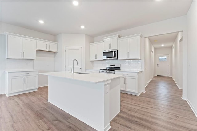 2208 Crestview Pl, Raymore, MO 64083 - kitchen featuring appliances with stainless steel finishes, a sink, a kitchen island with sink, white cabinetry, and recessed lighting
