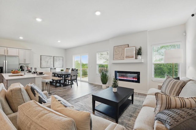2208 Crestview Pl, Raymore, MO 64083 - living area with light wood-style floors, a glass covered fireplace, recessed lighting, and baseboards