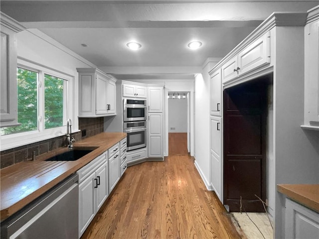 6317 Sherwood Ln, Shawnee, KS 66203 - kitchen featuring stainless steel appliances, a sink, wood finished floors, backsplash, and white cabinets