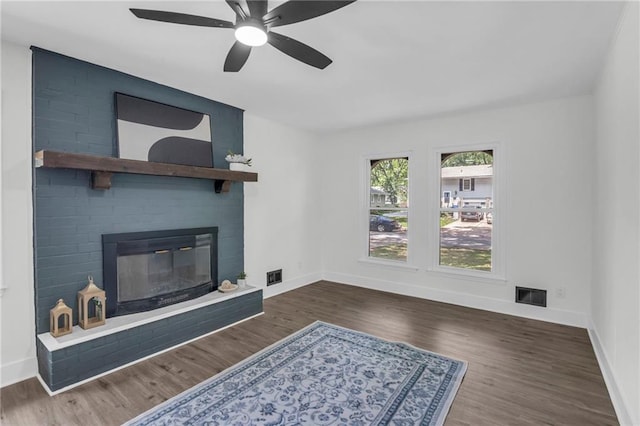 8823 E 111th St, Kansas City, MO 64134 - unfurnished living room with a large fireplace, baseboards, ceiling fan, and wood finished floors