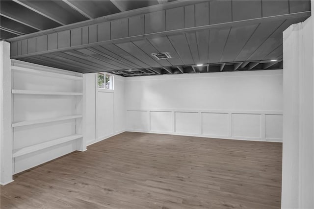 8823 E 111th St, Kansas City, MO 64134 - below grade area featuring wood finished floors, a decorative wall, and a wainscoted wall