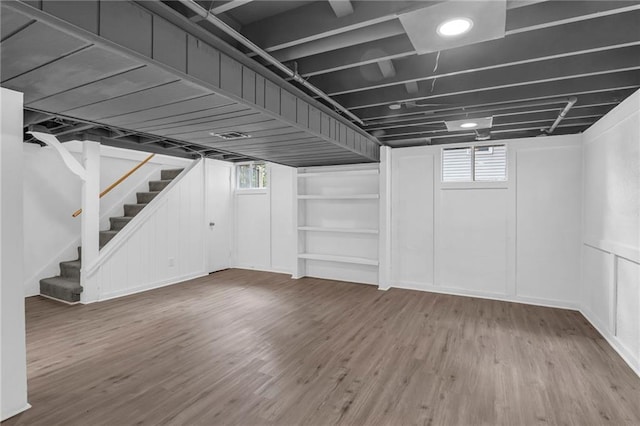 8823 E 111th St, Kansas City, MO 64134 - below grade area featuring stairs, healthy amount of natural light, and wood finished floors