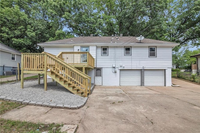 8823 E 111th St, Kansas City, MO 64134 - rear view of property featuring a garage, stairs, a wooden deck, and concrete driveway