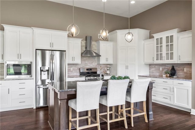 8756 Houston St, Lenexa, KS 66227 - kitchen featuring wall chimney range hood, stainless steel appliances, decorative backsplash, glass insert cabinets, and stone countertops