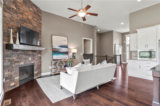 8756 Houston St, Lenexa, KS 66227 - living room featuring a ceiling fan, a stone fireplace, dark wood-style floors, recessed lighting, and a barn door