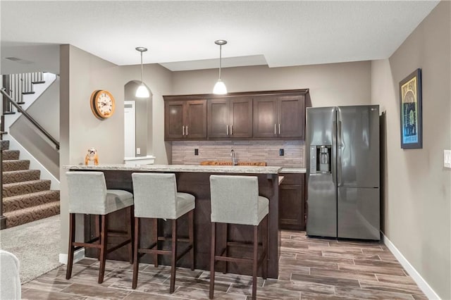 8756 Houston St, Lenexa, KS 66227 - kitchen featuring stainless steel fridge, dark brown cabinets, arched walkways, wood finished floors, and backsplash
