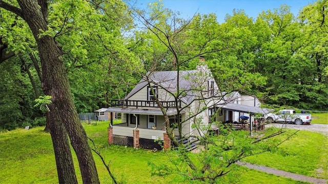 7508 Walnut St, Pleasant Valley, MO 64068 - view of front of home with a front yard, a chimney, dirt driveway, a porch, and a wooded view