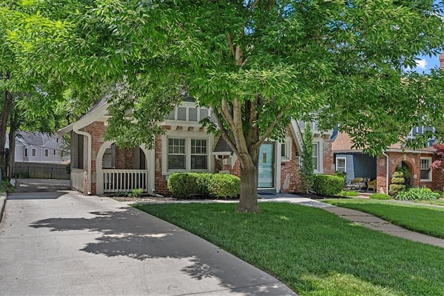 7224 Ward Pkwy, Kansas City, MO 64114 - obstructed view of property featuring a front yard, brick siding, driveway, and covered porch