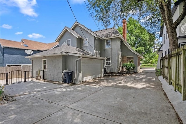 7224 Ward Pkwy, Kansas City, MO 64114 - rear view of property featuring a chimney, stucco siding, a gate, and a garage