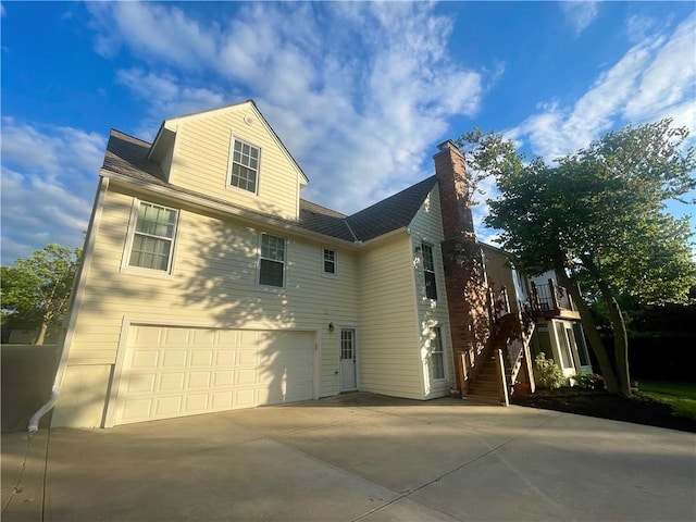 8122 Parkhill Rd, Lenexa, KS 66215 - rear view of property with an attached garage, a chimney, concrete driveway, and stairs