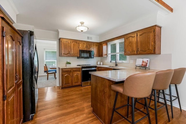 8122 Parkhill Rd, Lenexa, KS 66215 - kitchen featuring black appliances, a peninsula, brown cabinets, dark wood-type flooring, and tasteful backsplash