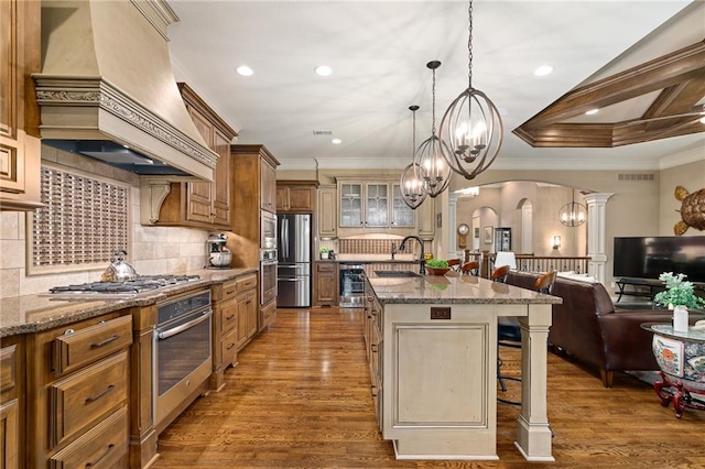 3116 W 137th St, Leawood, KS 66224 - kitchen with stainless steel appliances, custom exhaust hood, arched walkways, a sink, and a kitchen bar