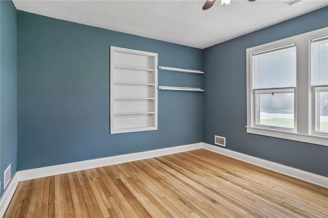 906 W 84th St, Kansas City, MO 64114 - unfurnished room featuring hardwood / wood-style floors, baseboards, a ceiling fan, and built in shelves