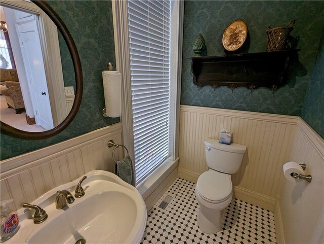 433 W State St, Troy, KS 66087 - half bath with wainscoting, wallpapered walls, toilet, and a sink