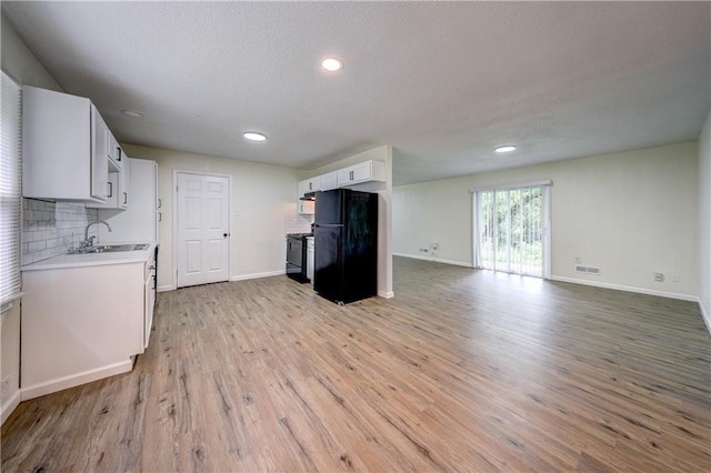 10711 Bennington Ave, Kansas City, MO 64134 - kitchen featuring black appliances, a sink, light countertops, light wood-style flooring, and white cabinetry