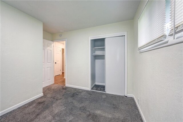 10711 Bennington Ave, Kansas City, MO 64134 - unfurnished bedroom featuring a textured wall, carpet, baseboards, and a closet