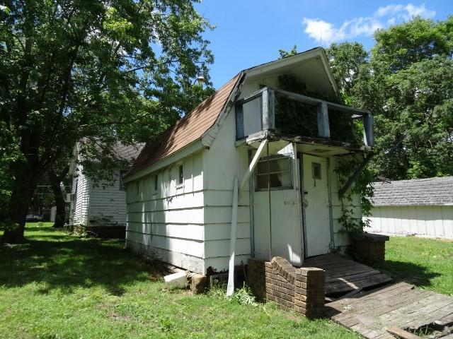 309-311 N Lyon St, Butler, MO 64730 - view of home's exterior featuring a lawn and a shingled roof
