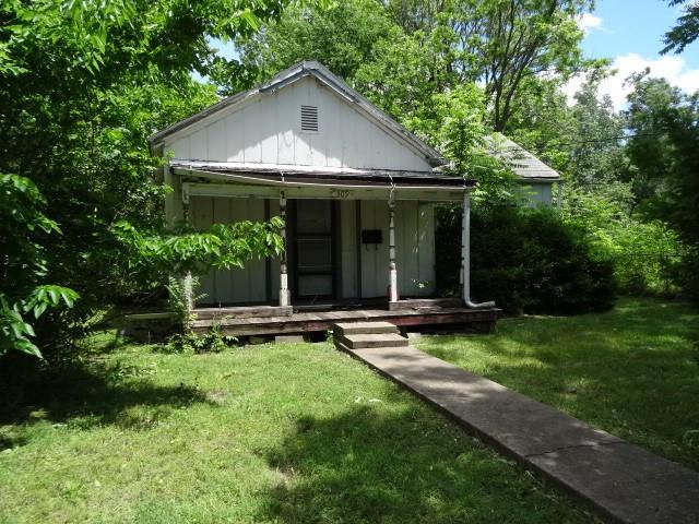 309-311 N Lyon St, Butler, MO 64730 - bungalow-style house with board and batten siding, a front yard, and a porch
