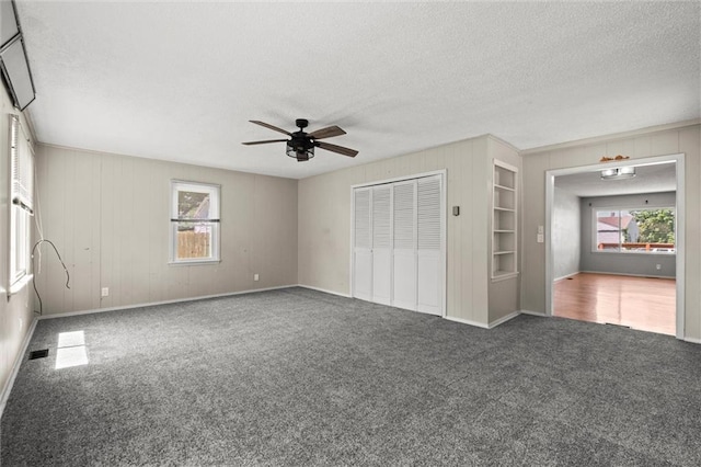 17207 E Swope Ln, Independence, MO 64056 - unfurnished living room with a ceiling fan, carpet flooring, a textured ceiling, built in shelves, and baseboards