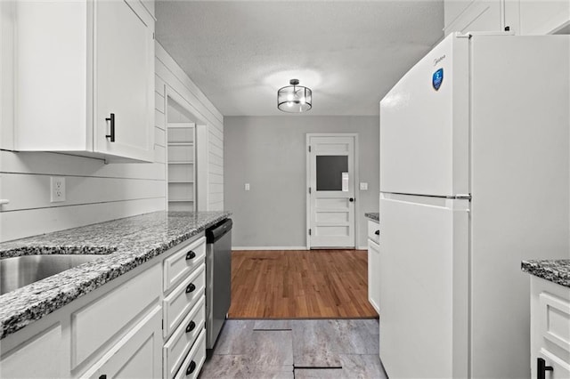 17207 E Swope Ln, Independence, MO 64056 - kitchen featuring freestanding refrigerator, white cabinetry, stainless steel dishwasher, light stone counters, and a textured ceiling