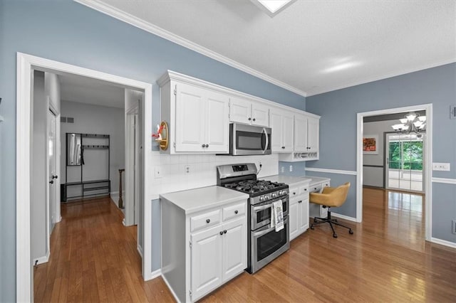 6221 W 126th Ter, Overland Park, KS 66209 - kitchen featuring stainless steel appliances, wood finished floors, light countertops, white cabinetry, and a chandelier