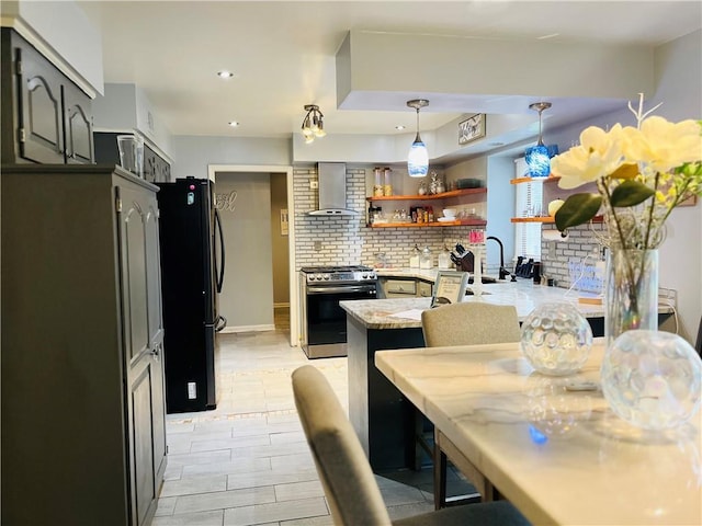 13106 E 57th St, Kansas City, MO 64133 - kitchen with stainless steel gas stove, freestanding refrigerator, wall chimney range hood, a peninsula, and light countertops