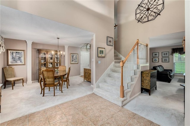 800 Ash Ct, Lansing, KS 66043 - dining space featuring carpet flooring, stairway, a chandelier, decorative columns, and a high ceiling