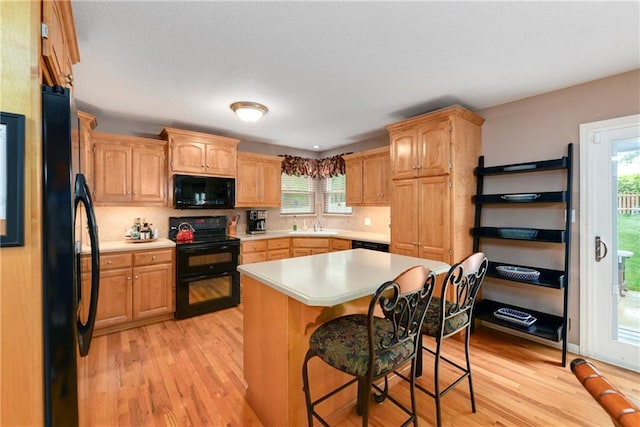 800 Ash Ct, Lansing, KS 66043 - kitchen with black appliances, light wood finished floors, light countertops, and a sink