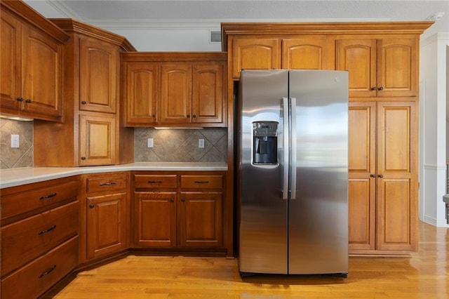 3104 SE 2nd St, Lees Summit, MO 64063 - kitchen with stainless steel fridge, light wood-style floors, brown cabinetry, and ornamental molding