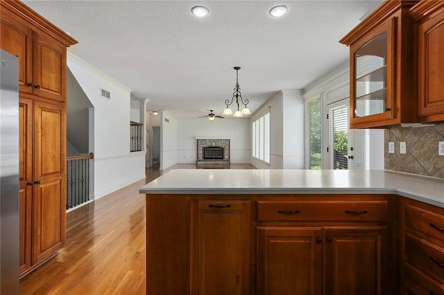 3104 SE 2nd St, Lees Summit, MO 64063 - kitchen featuring a fireplace, glass insert cabinets, decorative backsplash, light wood-type flooring, and a peninsula