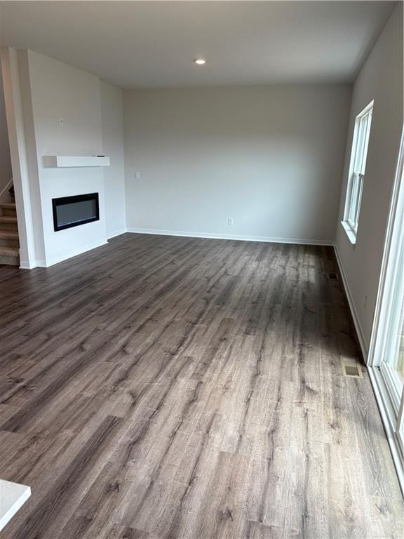 19620 W 201st St, Spring Hill, KS 66083 - unfurnished living room featuring dark wood-style flooring, a glass covered fireplace, baseboards, plenty of natural light, and recessed lighting