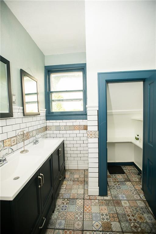 1017 Angelique St, Saint Joseph, MO 64501 - bathroom featuring double vanity, tile walls, and a wainscoted wall
