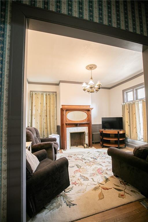 1017 Angelique St, Saint Joseph, MO 64501 - living area featuring radiator heating unit, ornamental molding, a chandelier, and wood finished floors